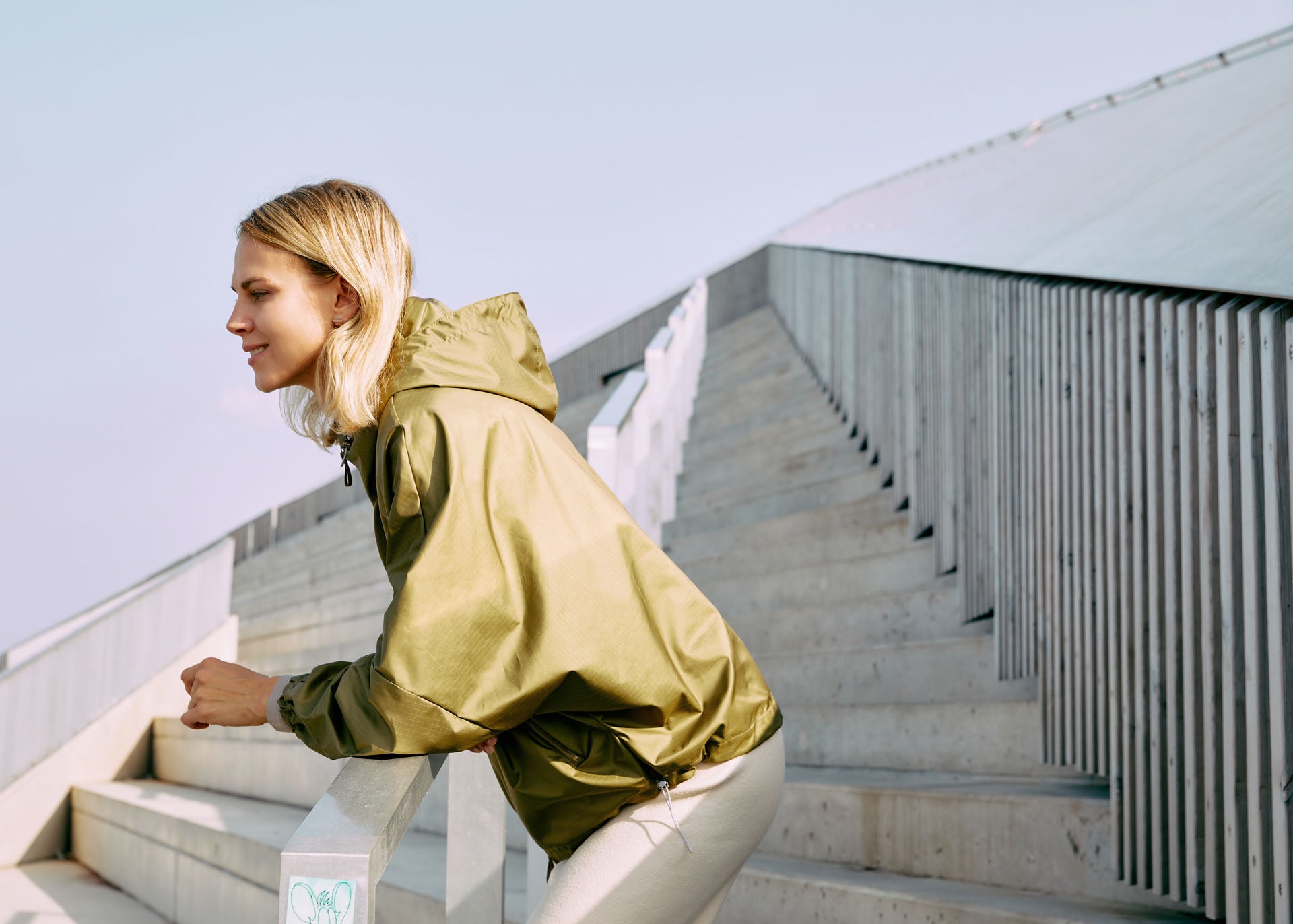 Woman wearing a hooded windbreaker jacket in green color 