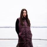 a lady wearing a long, luxurious puffer vest in burgundy color 
