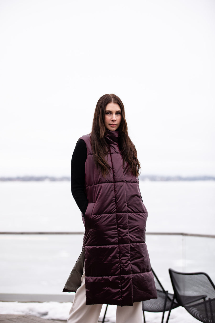 a lady wearing a long, luxurious puffer vest in burgundy color 