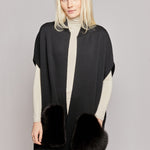 A woman wearing a black vest made from merino wool with luxurious fox fur pockets 
