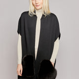 A woman wearing a black vest made from merino wool with luxurious fox fur pockets 