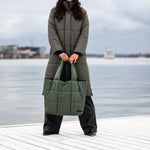 A woman holding a large olive green tote bag 