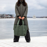A woman holding a large olive green tote bag 