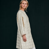 Woman wearing a light quilted coat in a nice light yellow color 
