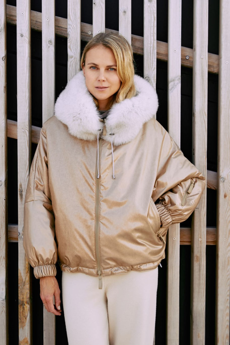 a woman wearing a ski jacket made from fox fur in gold color.
  