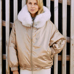 a woman wearing a ski jacket made from fox fur in gold color.
  