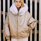 a woman wearing a ski jacket made from fox fur in gold color.
  