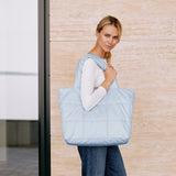 a woman holding a large tote bag in light color 