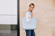 a woman holding a large tote bag in light color 