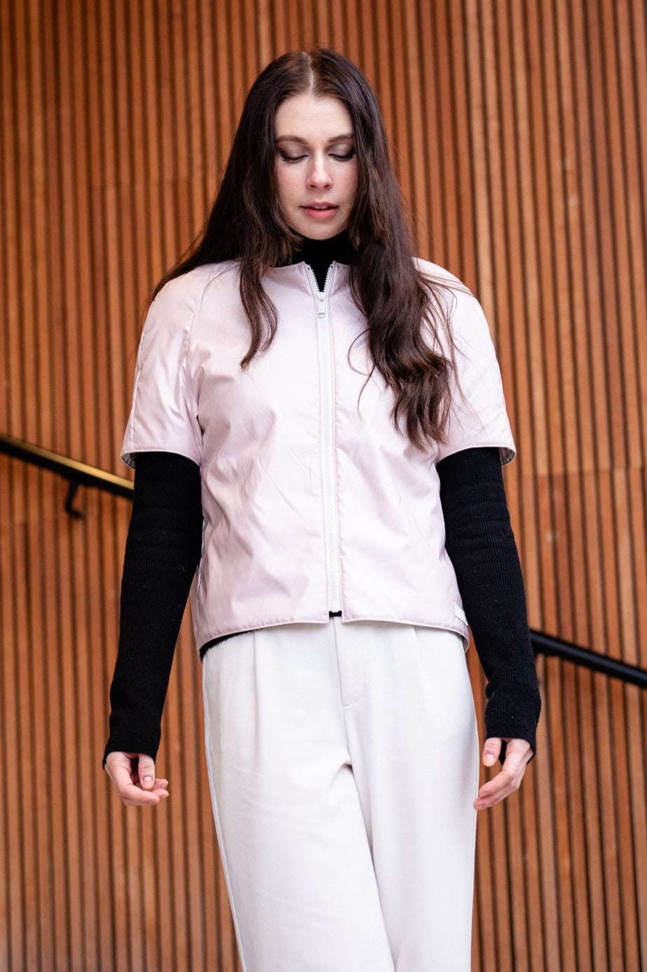 a woman wearing a light padded jacket with short sleevs and zipper closing 