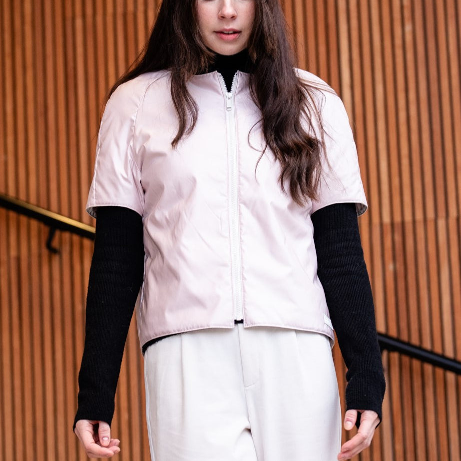 a woman wearing a light padded jacket with short sleevs and zipper closing 