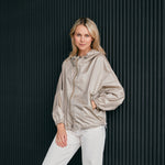 woman wearing a contemporary beige windbreaker jacket with hood  