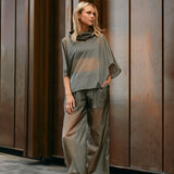 Woman wearing light, sheer green windbreaker poncho and pants 