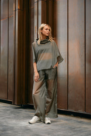 Woman wearing light, sheer green windbreaker poncho and pants 