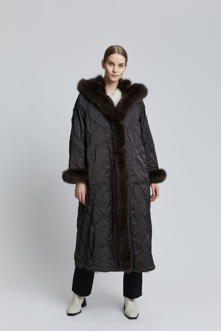  A-lined reversible black fur coat has a large hood, fur trim along the front and hood, fur cuffs and a braided pattern