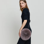 Lady modelling a Round fox fur cross-body and wrist bag.