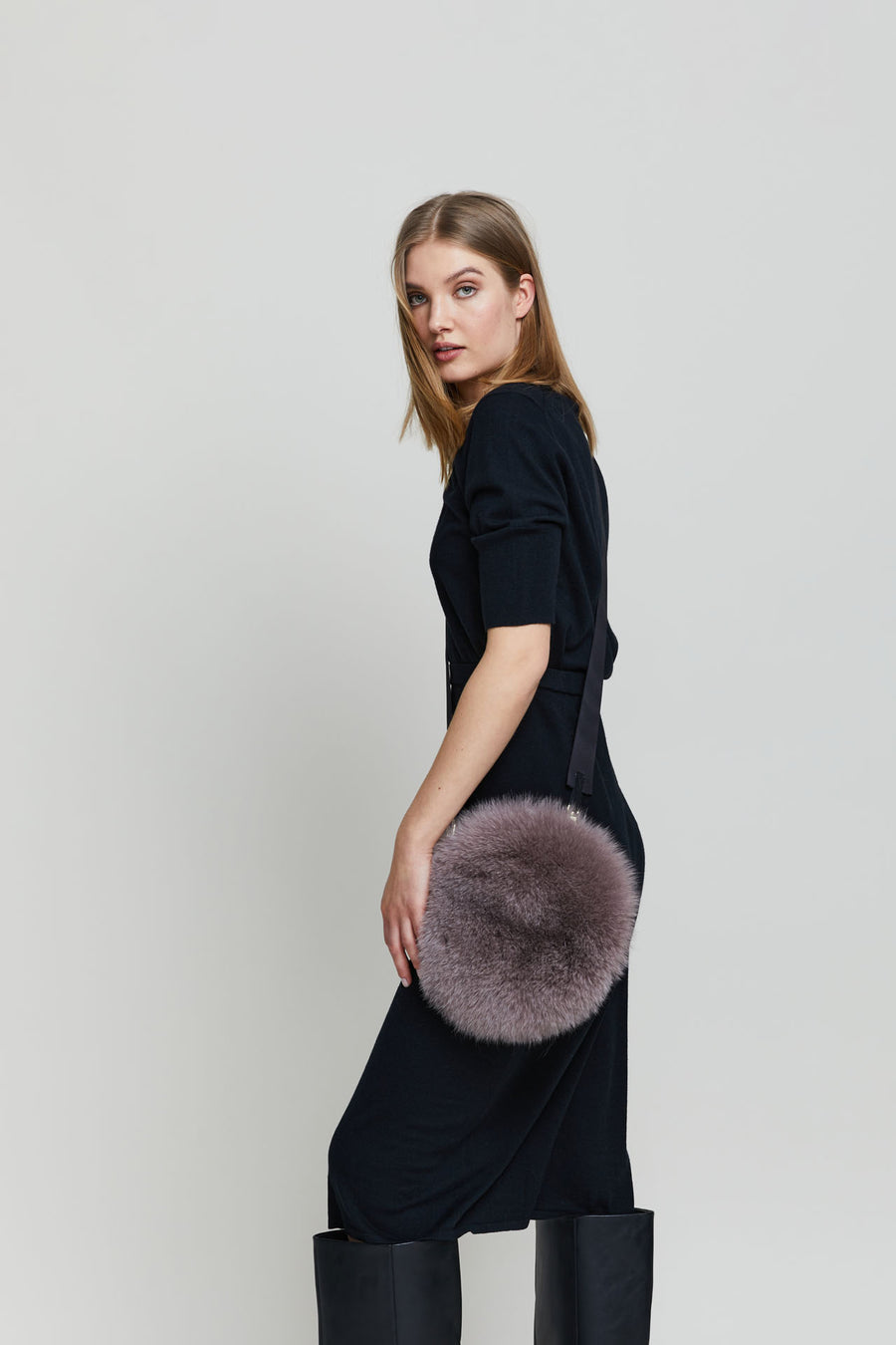 Lady modelling a Round fox fur cross-body and wrist bag.