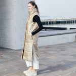 Lady modeling a limited edition vest is made from windproof and water repellent fabrics, with a soft down-like nonwoven lining. The vest has a collar and push button closing. 