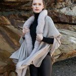Young woman standing on a beach wearing a beige Gemmi cashmere wrap with fox fur